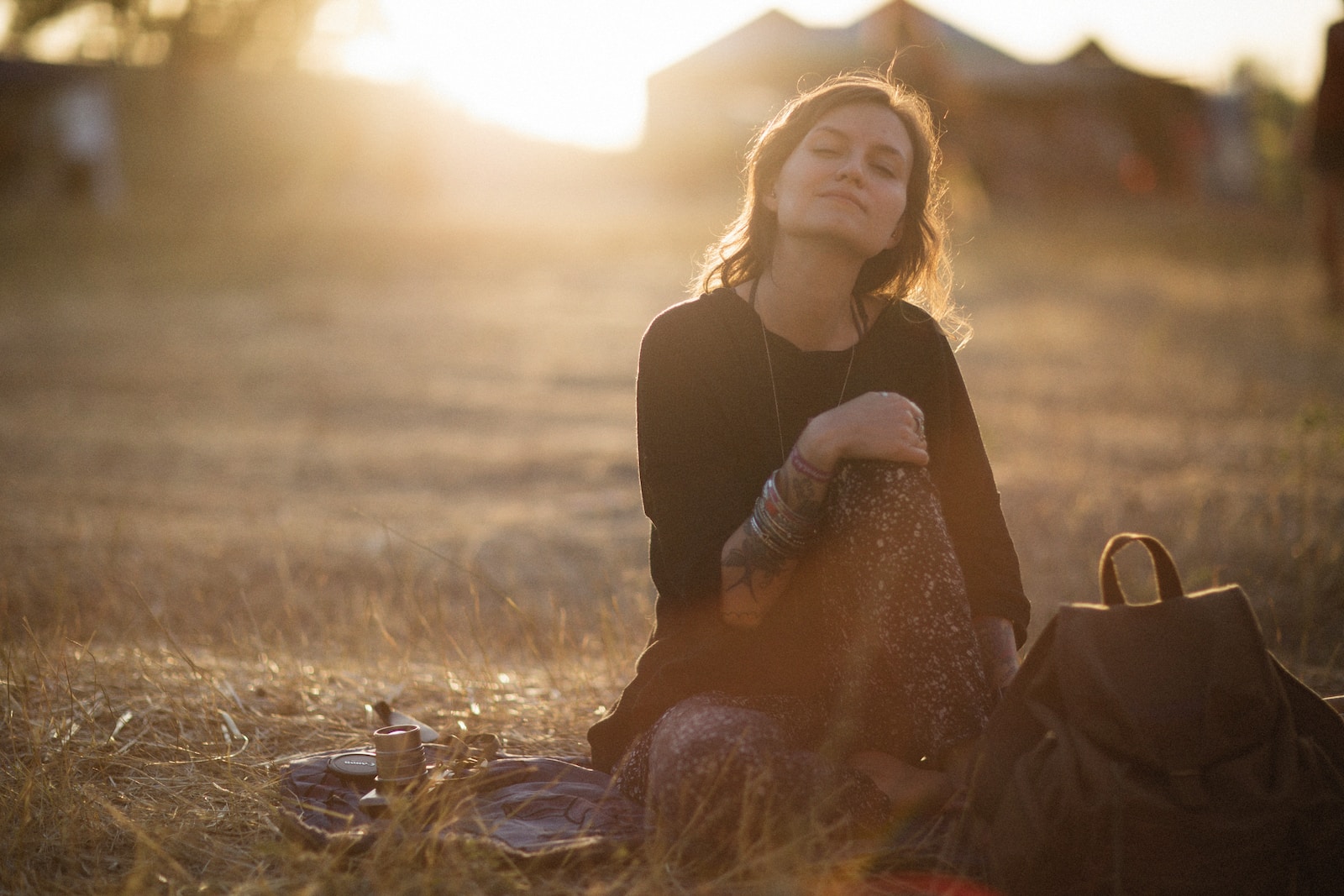 a woman sitting in a field with a backpack