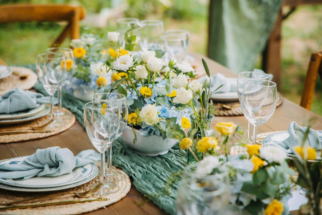 Outdoor table setting with floral centerpiece and greenery centerpiece arrangements